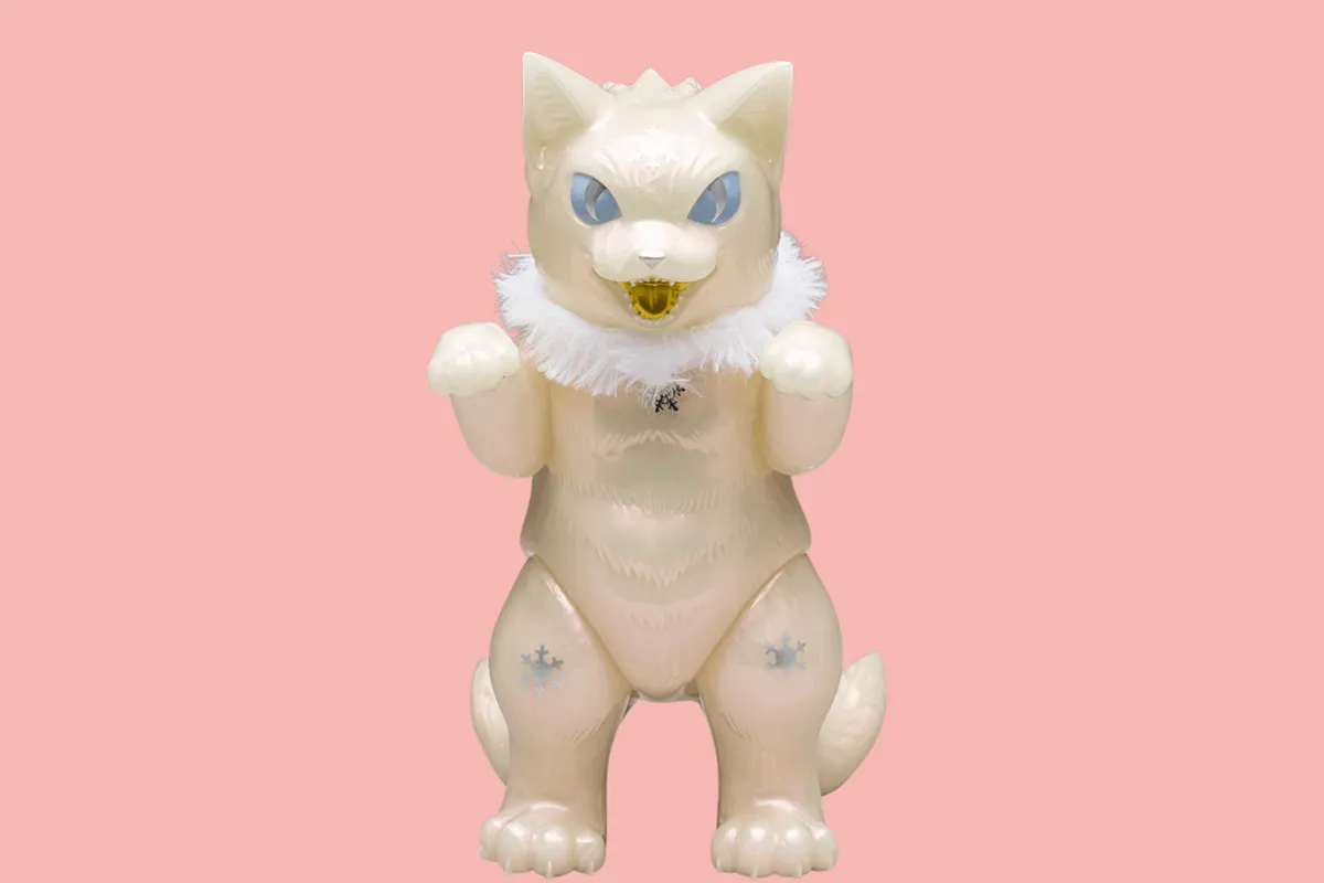 Pearlescent white “Snow Pearl” cat figure with blue eyes, fluffy white collar, and upright paws against a soft pink background.