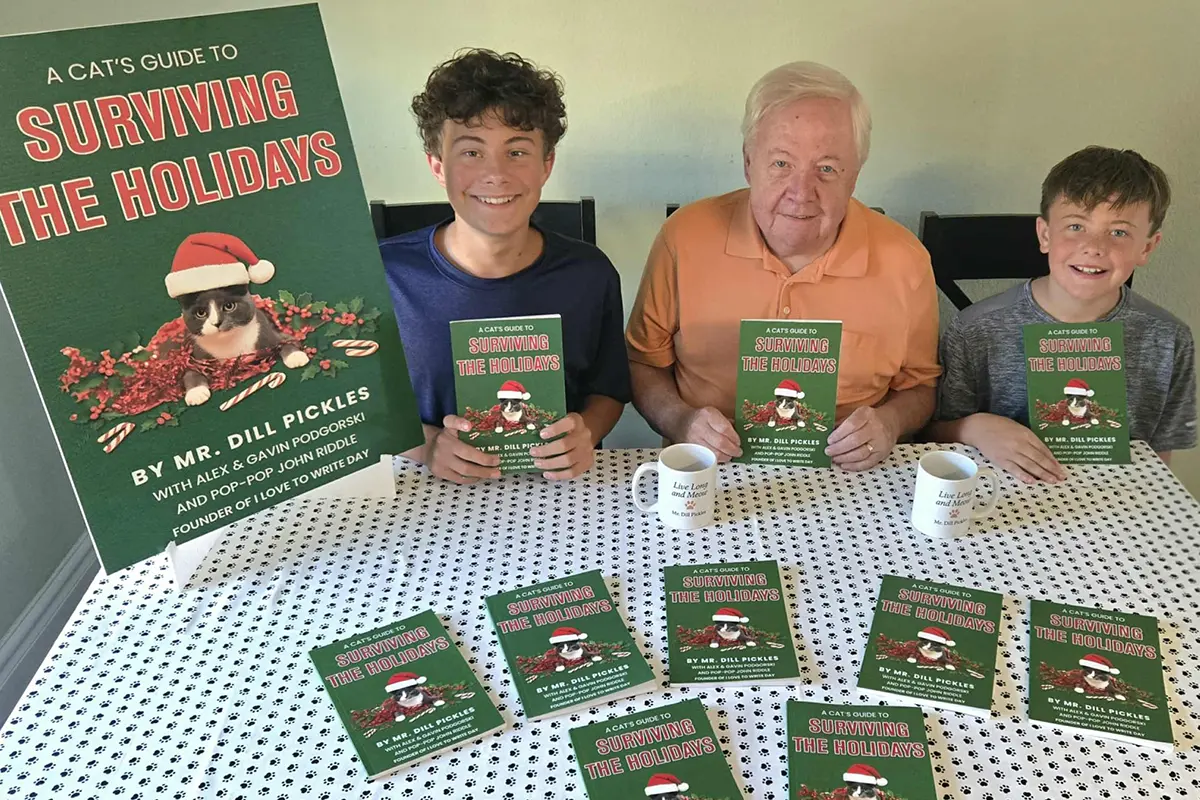 John Riddle with grandsons Gavin and Alex holding copies of A Cat’s Guide to Surviving the Holidays by Mr. Dill Pickles.