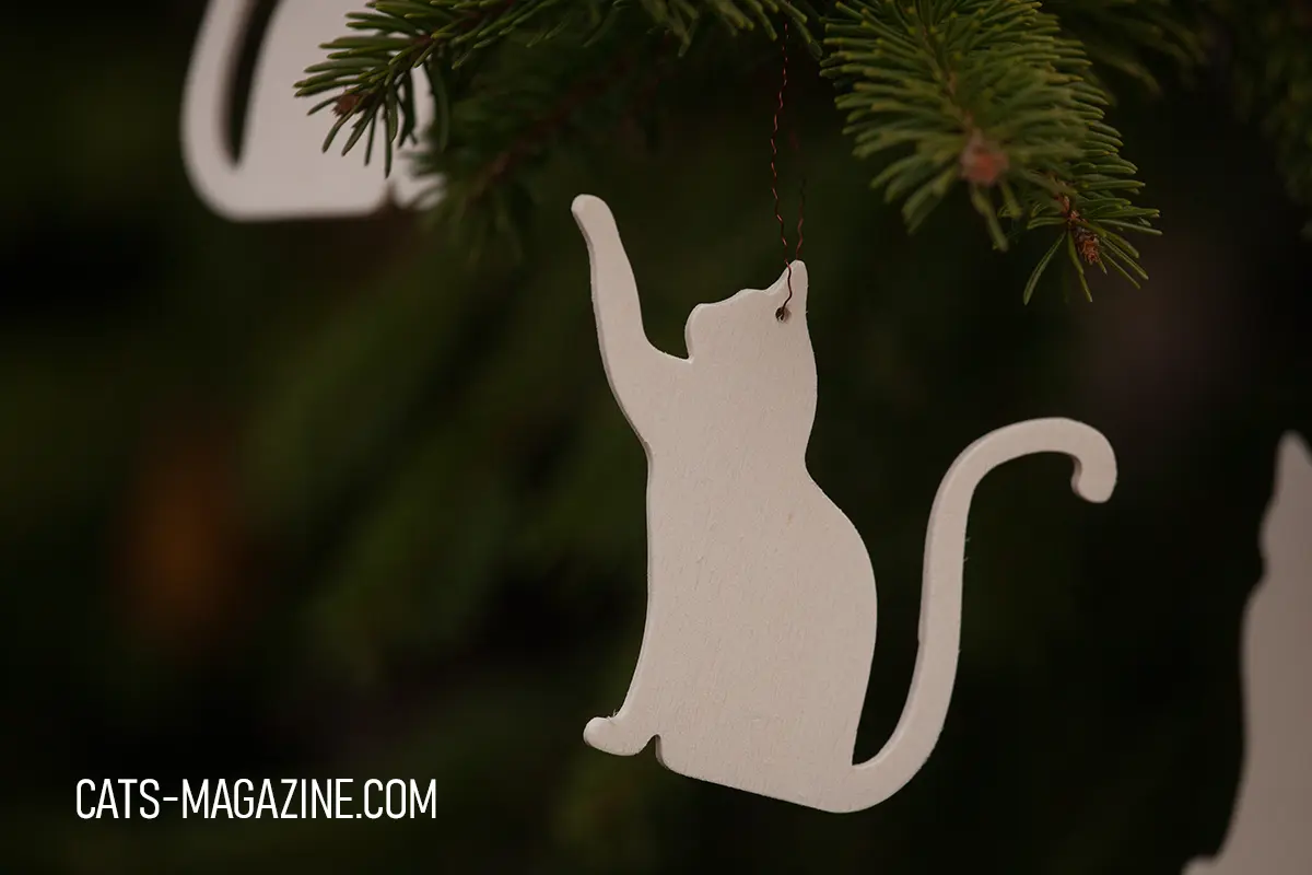 Handmade wooden cat ornament hanging on evergreen branch, Cats Magazine shop