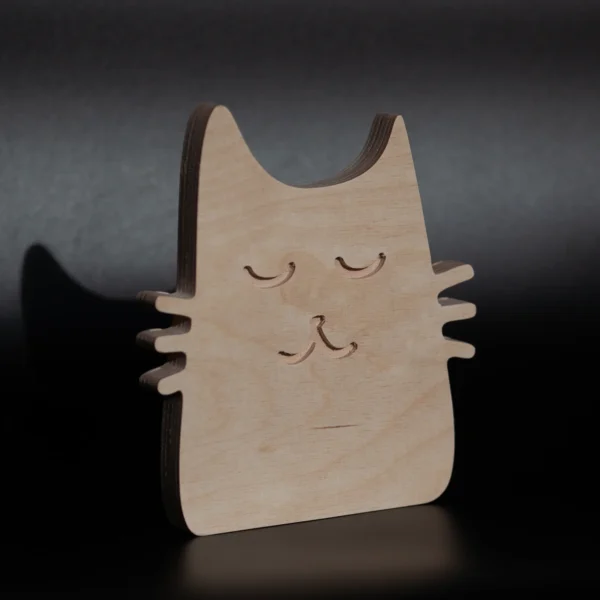 Minimalist handmade plywood cat decor photographed on dark background