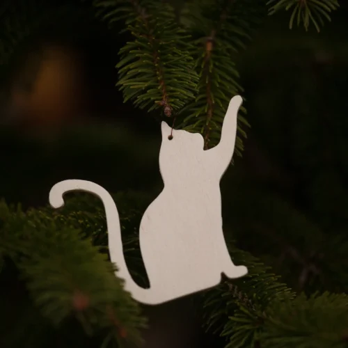 Set of handmade wooden cat ornaments hanging on evergreen branches