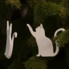 Zen Cat Wooden Ornaments Two minimalist wooden cat ornaments hanging on evergreen branches